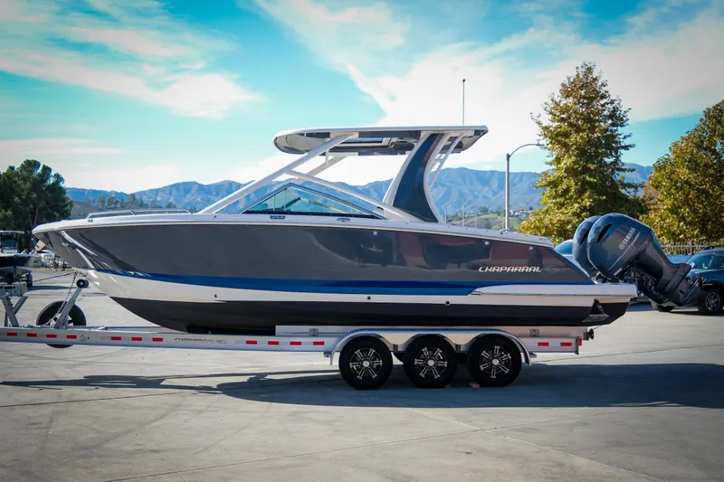 Slide: The Image of 2021 Chaparral 280 OSX boat on trailer, parked outdoors under a clear blue sky. - 5
