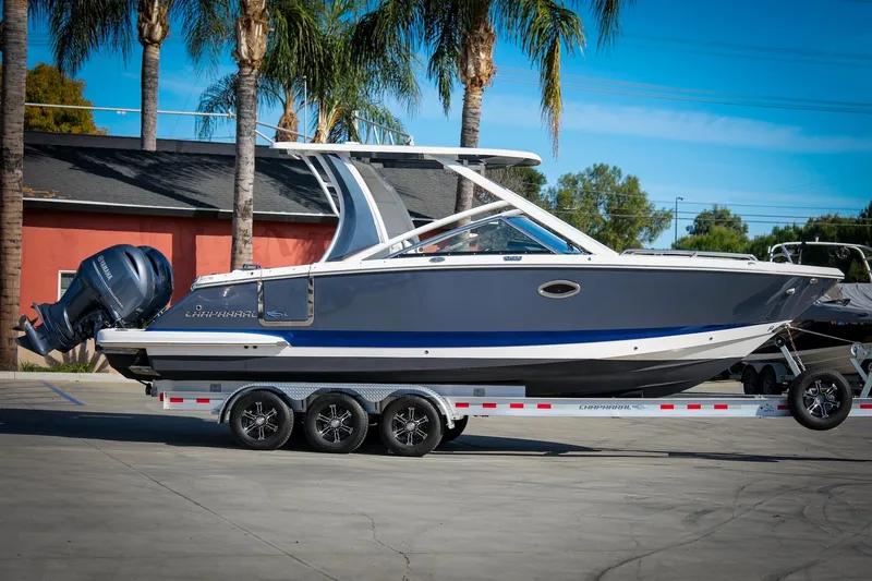 Slide: The Image of 2021 Chaparral 280 OSX boat on trailer, parked outdoors with palm trees in background. - 8