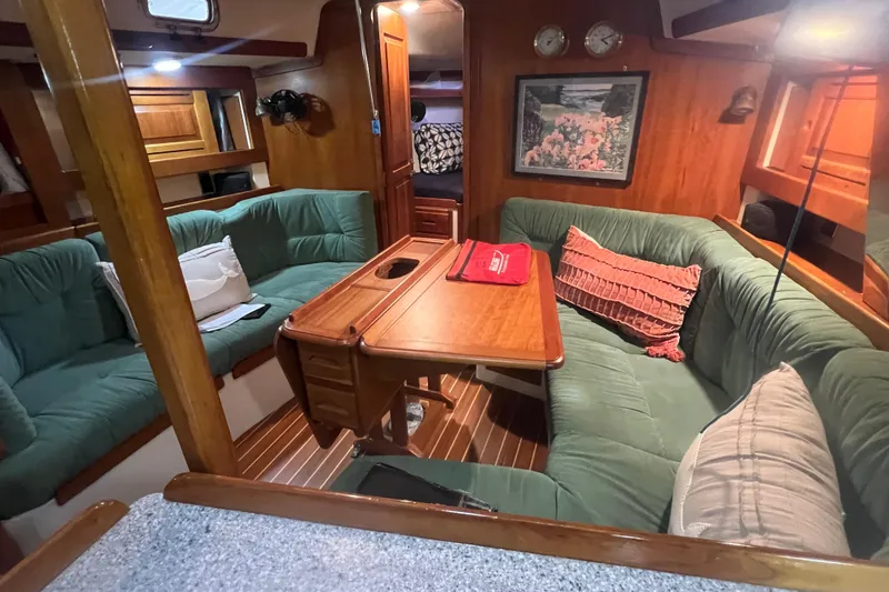Slide: The Image of Cozy interior of 2001 Tartan 3700 Sloop with green seating and wooden table. - 2