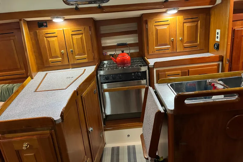 Slide: The Image of Cozy 2001 Tartan 3700 Sloop kitchen with wooden cabinets and stainless steel appliances. - 3