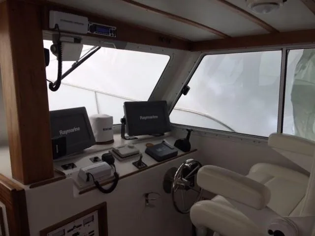 Slide: The Image of 2003 Wesmac Flybridge helm with Raymarine electronics and dual white captain chairs. - 21