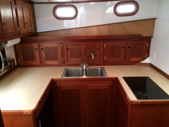 Slide: The Image of 2003 Wesmac Flybridge kitchen with wooden cabinets, sink, and stovetop. - 24