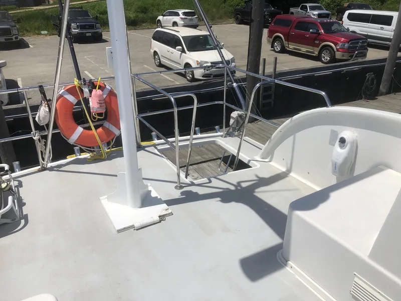 Slide: The Image of 2003 Wesmac Flybridge boat deck with life preserver, docked near parked cars. - 31