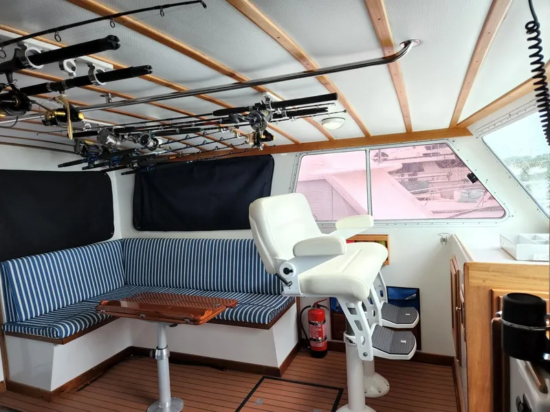 Slide: The Image of 2003 Wesmac Flybridge interior with striped seating, fishing rods, and captain's chair. - 41