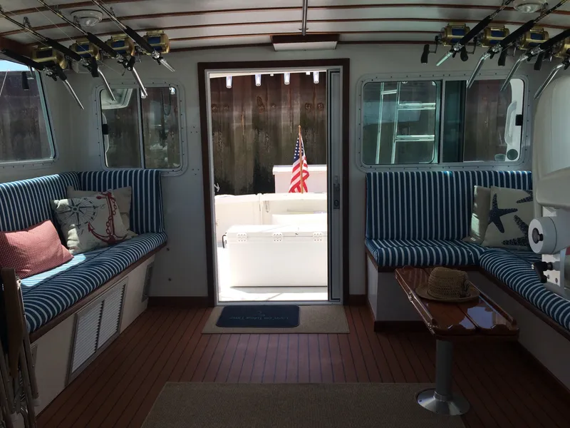 Slide: The Image of 2003 Wesmac Flybridge interior with striped seating, fishing rods, and American flag. - 44