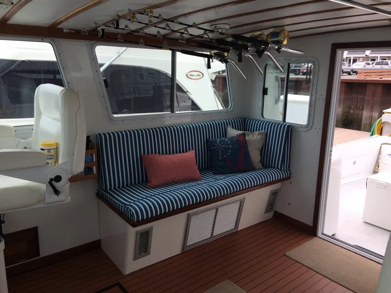 Slide: The Image of 2003 Wesmac Flybridge interior with striped seating and fishing rods. - 49