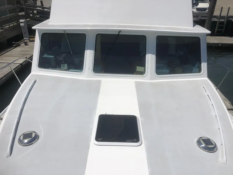 Slide: The Image of 2003 Wesmac Flybridge boat with white deck and windows at a marina. - 6