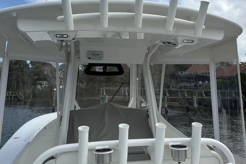 Slide: The Image of 2023 Regulator 34 boat with rod holders and canopy, docked by a wooded shoreline. - 13