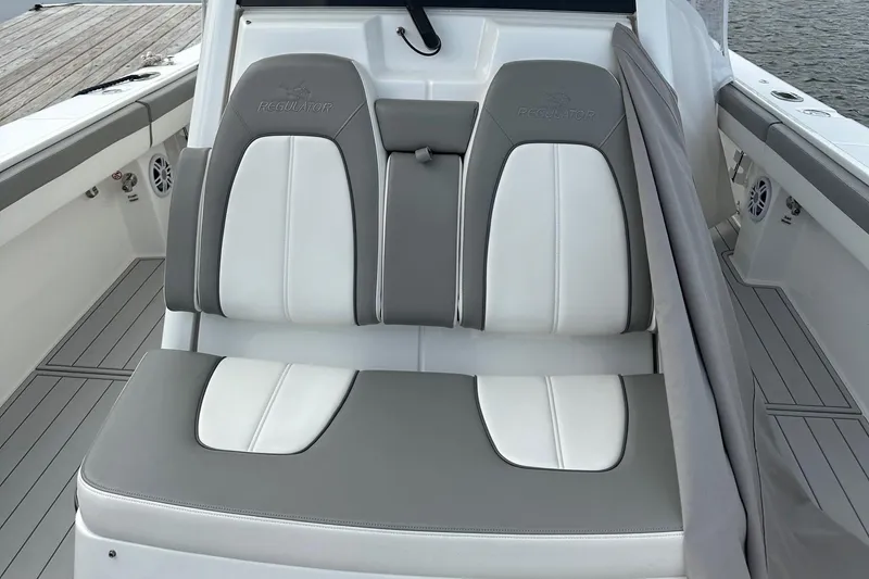 Slide: The Image of 2023 Regulator 34 boat seating with gray and white upholstery, dockside view. - 18