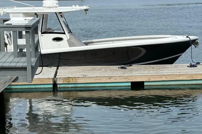 Slide: The Image of 2023 Regulator 34 boat docked on calm water. - 2