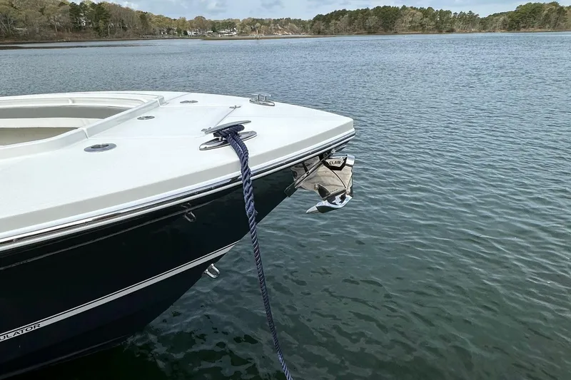 Slide: The Image of 2023 Regulator 34 boat anchored on calm water with scenic background. - 6