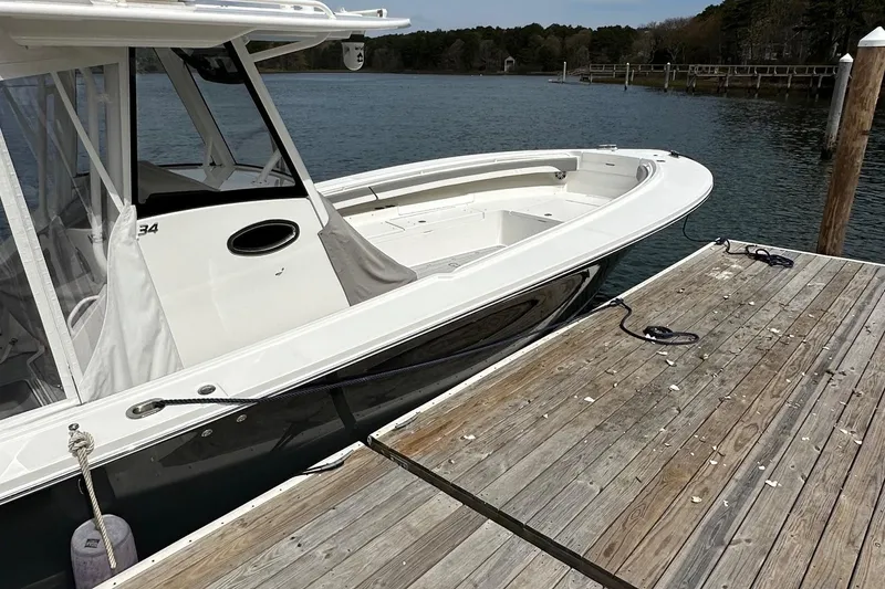 Slide: The Image of 2023 Regulator 34 boat docked by a wooden pier on a calm lake. - 7