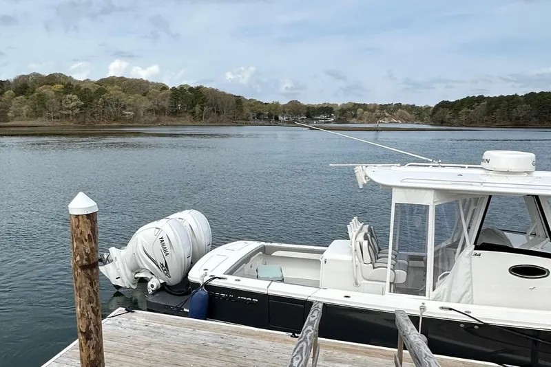 Slide: The Image of 2023 Regulator 34 boat docked by a serene lake with wooded shoreline. - 9