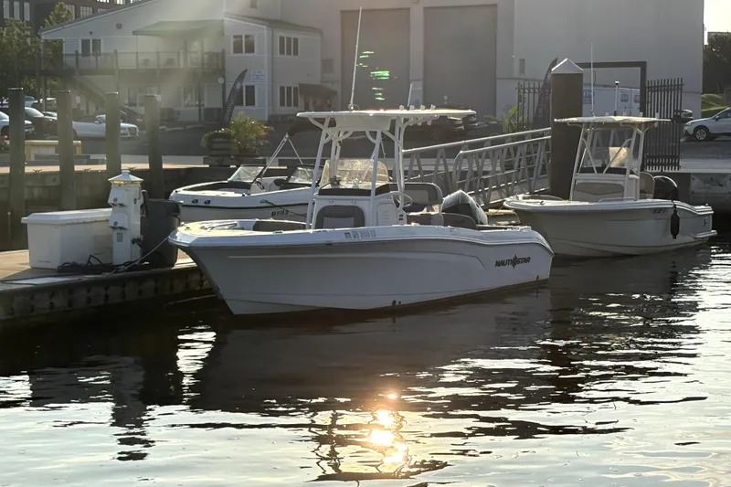 The Image of 2024 NauticStar 222L Offshore boat docked at marina in sunlight. - 1
