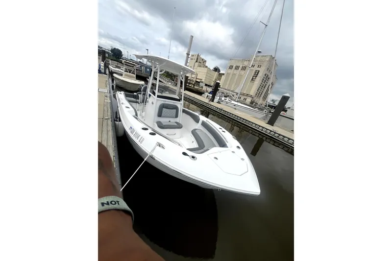 Slide: The Image of 2024 NauticStar 222L Offshore boat docked at marina under cloudy sky. - 2