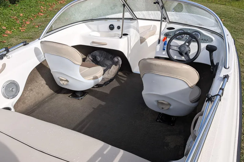 Slide: The Image of 2016 Bayliner 160 Bowrider interior with steering wheel and seating, parked on grass. - 3
