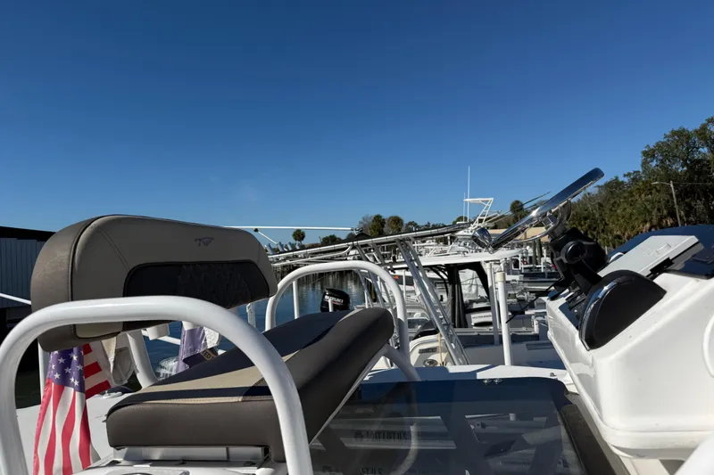 Slide: The Image of 2022 Tidewater 2500 Carolina Bay boat with steering console and seating, under clear blue sky. - 14