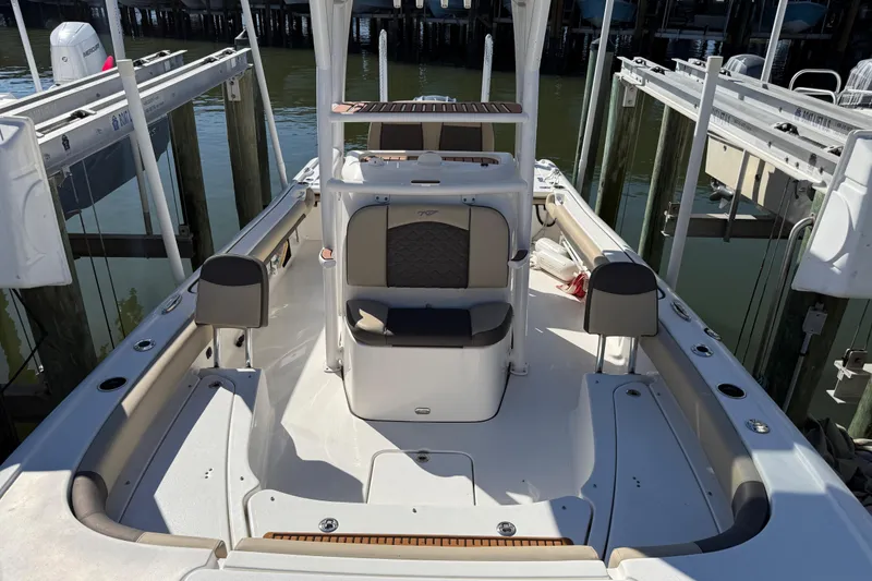 Slide: The Image of 2022 Tidewater 2500 Carolina Bay boat interior with seating and storage, docked by the water. - 5
