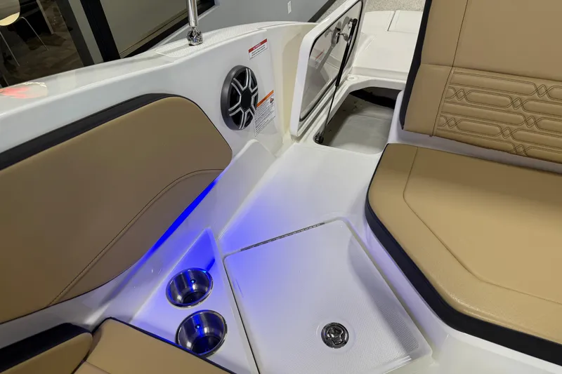 Slide: The Image of 2026 Sea Ray SPX 210 Outboard interior with tan seating, cup holders, and blue LED lighting. - 24