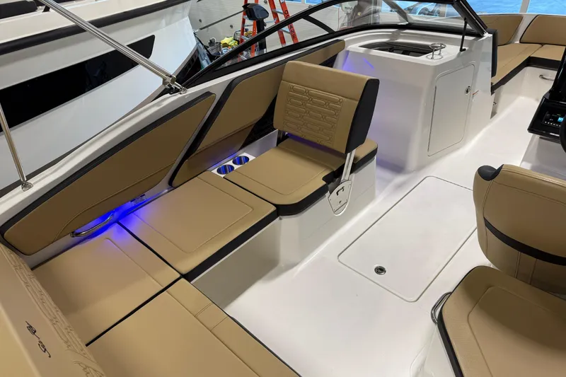 Slide: The Image of 2026 Sea Ray SPX 210 Outboard boat interior with tan seating and blue accent lighting. - 28