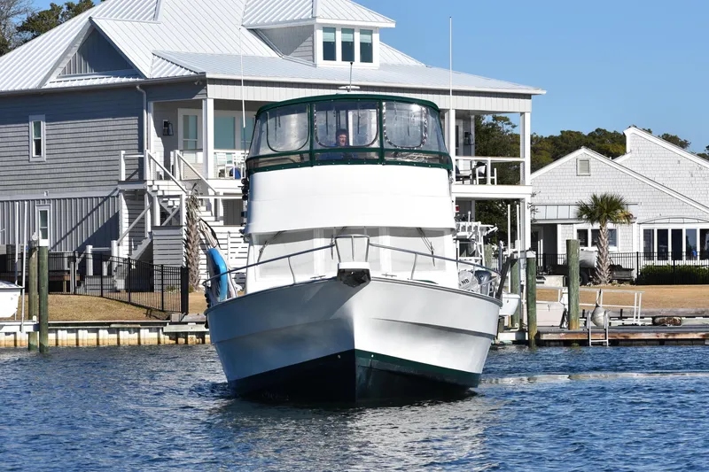 Slide: The Image of 2001 Mainship 390 yacht docked near waterfront homes on a sunny day. - 2