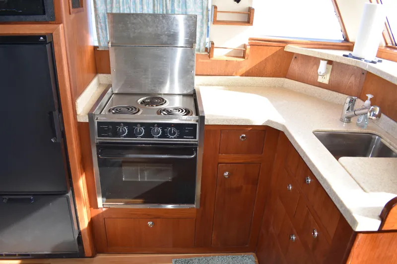 Slide: The Image of 2001 Mainship 390 yacht kitchen with stove, sink, and wooden cabinetry. - 21