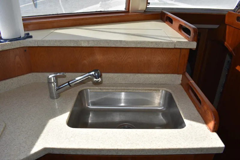 Slide: The Image of 2001 Mainship 390 yacht kitchen sink with modern faucet and wooden cabinetry. - 22