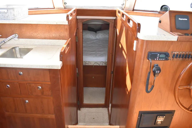 Slide: The Image of 2001 Mainship 390 interior with wood cabinetry, sink, and cozy sleeping area. - 23