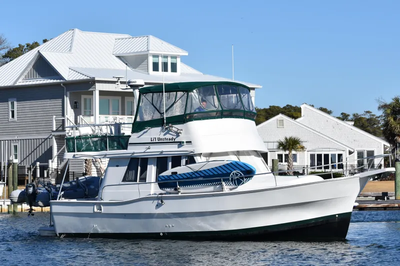 Slide: The Image of 2001 Mainship 390 yacht docked near waterfront homes on a sunny day. - 3