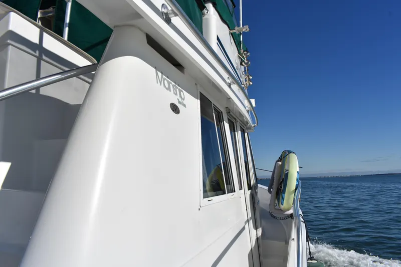 Slide: The Image of 2001 Mainship 390 yacht cruising on open water under clear blue sky. - 44