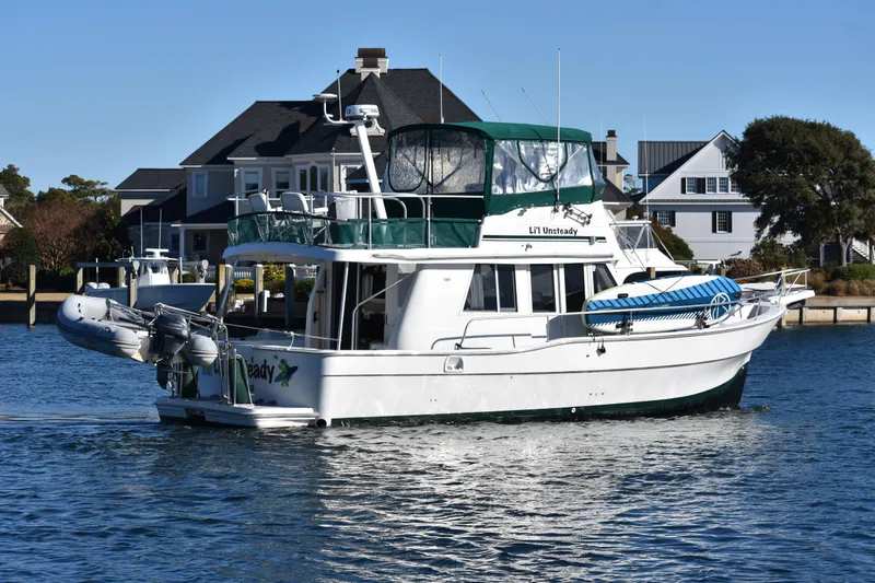 Slide: The Image of 2001 Mainship 390 yacht cruising near waterfront homes on a sunny day. - 5