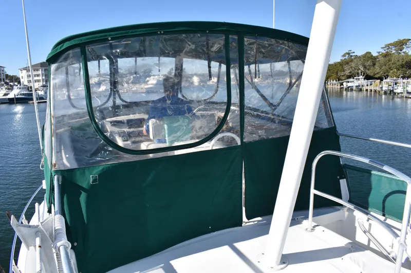 Slide: The Image of 2001 Mainship 390 boat with green canopy docked in a marina. - 58