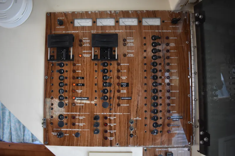 Slide: The Image of Electrical control panel on a 2001 Mainship 390 boat, featuring various switches and meters. - 73
