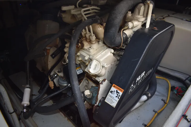 Slide: The Image of Engine compartment of a 2001 Mainship 390 boat, showcasing mechanical components and hoses. - 83