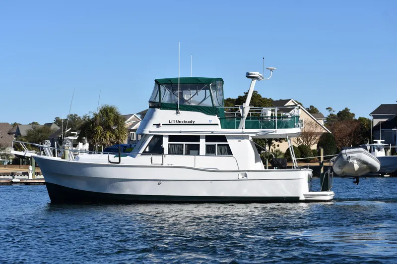 Slide: The Image of 2001 Mainship 390 yacht docked in a marina, featuring a green canopy. - 9