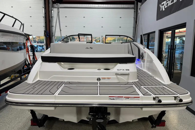 Slide: The Image of 2026 Sea Ray SPX 210 boat in showroom, rear view with sleek design and modern features. - 11