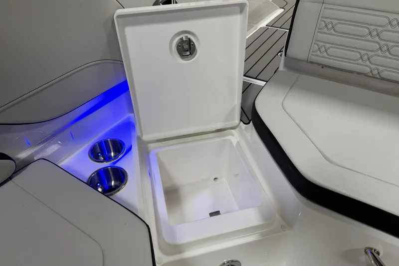 Slide: The Image of 2026 Sea Ray SPX 210 boat interior with open storage compartment and cup holders. - 24