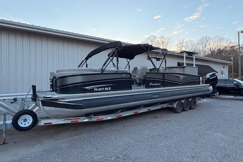 Slide: The Image of 2021 Premier 310 Accolade pontoon boat on trailer near building. - 1