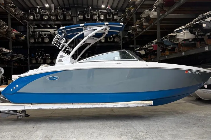 The Image of 2018 Cobalt R5 Surf boat in storage, featuring a sleek blue and gray design. - 2