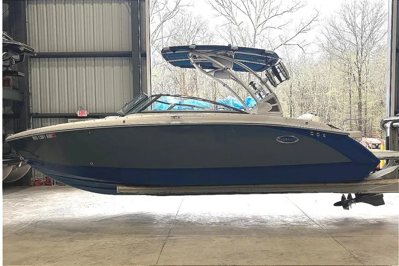 Slide: The Image of 2018 Cobalt R5 Surf boat in storage, blue and white exterior, side view. - 4