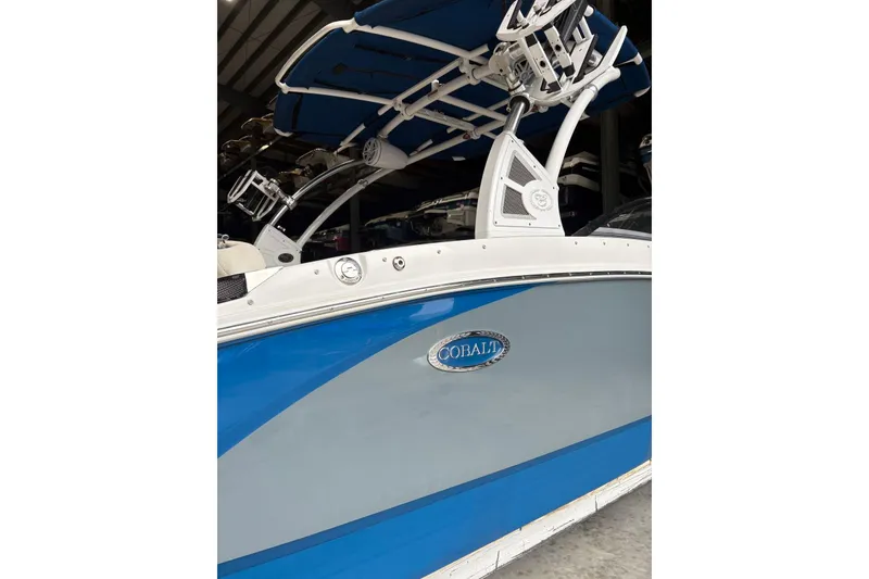 Slide: The Image of 2018 Cobalt R5 Surf boat with blue and gray exterior in storage. - 8