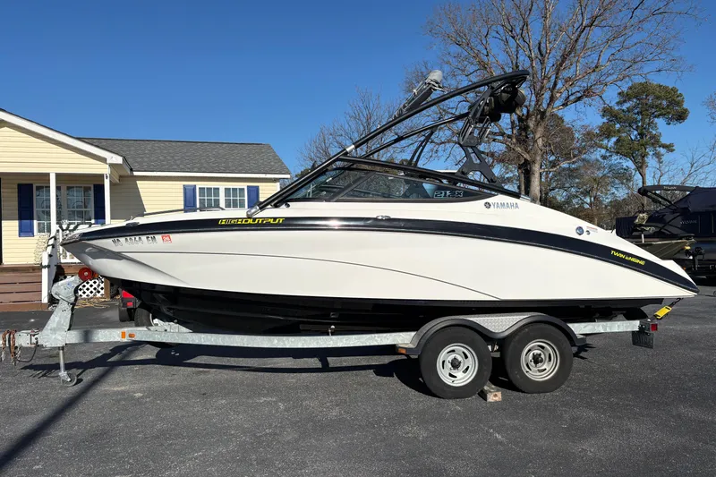 Slide: The Image of 2015 Yamaha Boats 212X on trailer, parked outdoors near a house. - 6