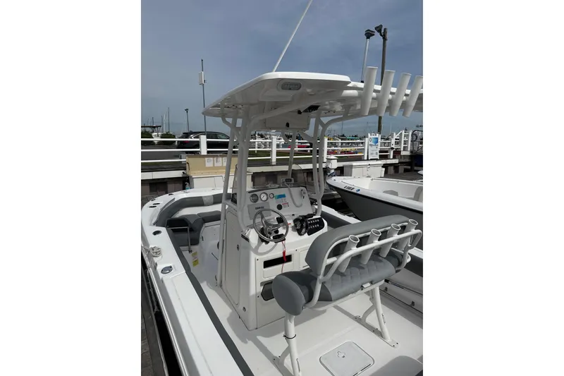 Slide: The Image of 2024 NauticStar 222L Offshore boat interior with helm and seating at a marina. - 4