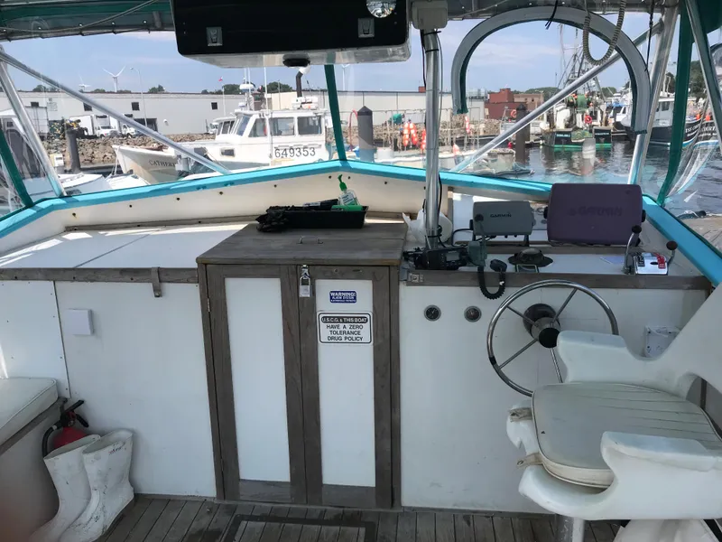 Slide: The Image of 1988 JC Provincetown boat helm with steering wheel and control panel at a marina. - 8