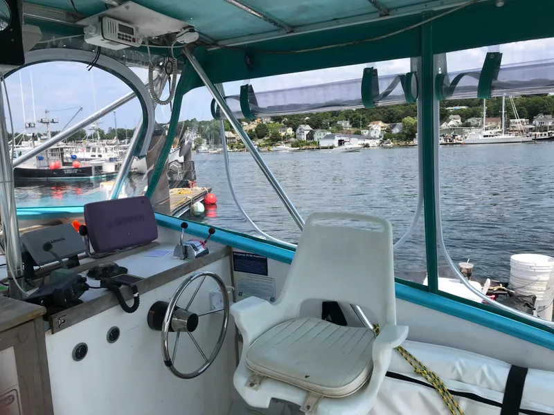 Slide: The Image of 1988 JC Provincetown boat interior with steering wheel and captain's chair, docked at marina. - 9