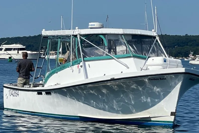 The Image of 1988 JC Provincetown boat "Yankee Rose" on water, person fishing, clear day. - 0