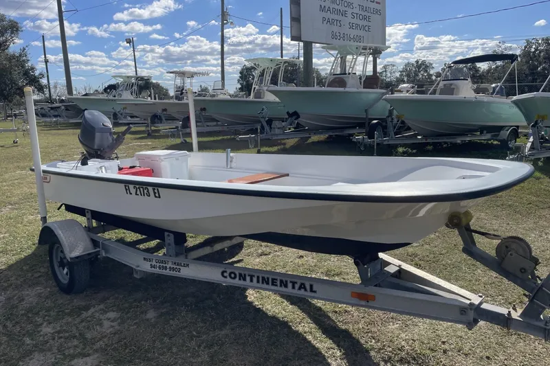 Slide: The Image of 1985 Boston Whaler 15' boat on trailer, parked outdoors under a clear sky. - 0