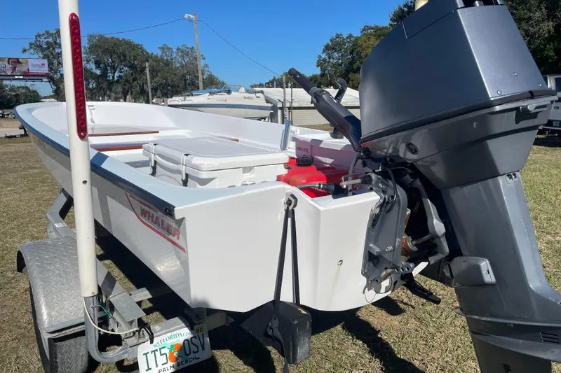 Slide: The Image of 1985 Boston Whaler 15' boat on trailer with outboard motor, parked outdoors. - 10