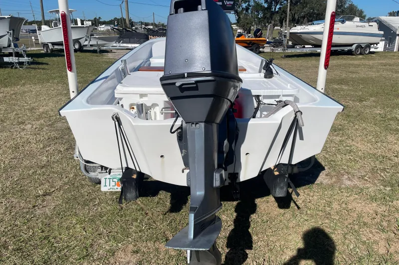 Slide: The Image of 1985 Boston Whaler 15' boat with outboard motor on trailer, parked on grass. - 11