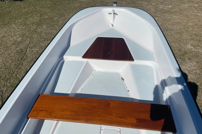 Slide: The Image of 1985 Boston Whaler 15' boat interior with wooden seats, on grassy ground. - 5